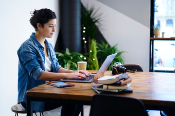 Beautiful young woman typing text information on modern laptop device in searching information on...