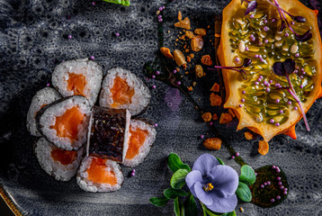 sushi roll with salmon and rice in plate on black wooden table background