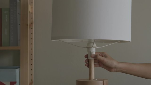 Hand Of A Woman Is Turning On Or Turning Off Lamp Inside The House