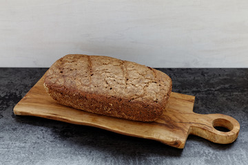 Homemade sourdough bread loaf on wooden olive wood board at black table. Baking own bread at home.