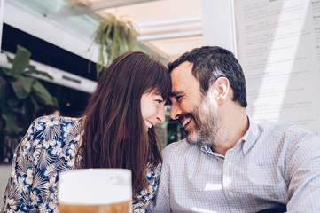 Young and attractive couple smiling with their heads together during a celebration meal