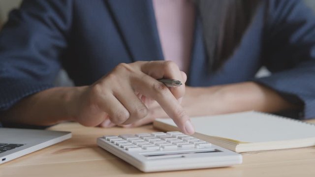 Hand of a businesswoman using a calculator on desk in the office