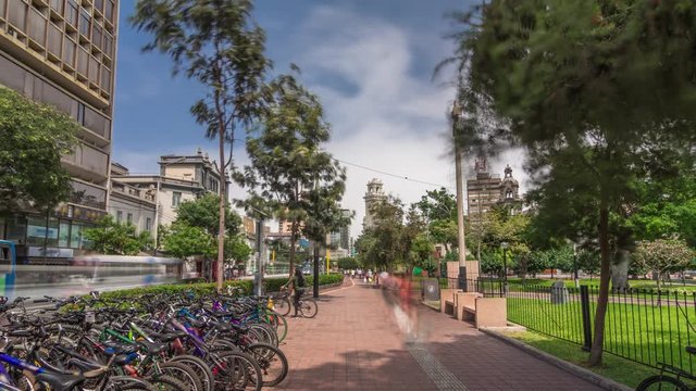 Red cycling track in the Jose Larco avenue and bicycle parking timelapse hyperlapse in Miraflores, Lima Peru. Central park on the right side and traffic on the street
