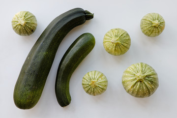 Flat lay of different shape zucchini vegetable. Round and long courgette veg on bright background.