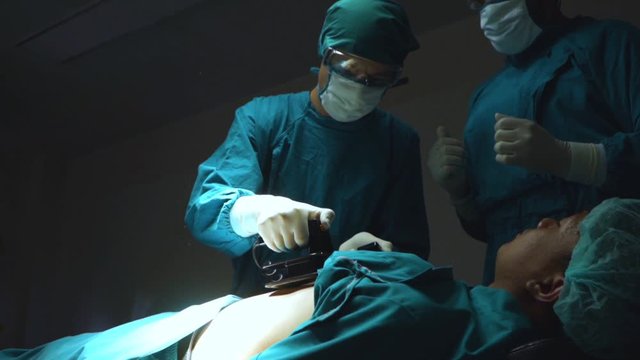 Doctors use defibrillator to revive male patient in the opeating theater.