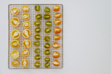 Fresh tomatoes on dehydration tray. Texture made of halved ripe tomatoes (various heirlooms). Top view, copy space.
