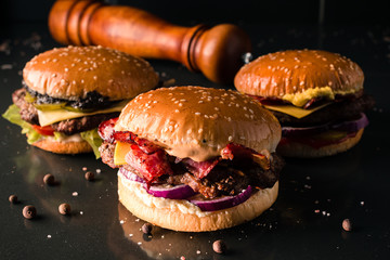 row of three burgers on a dark background