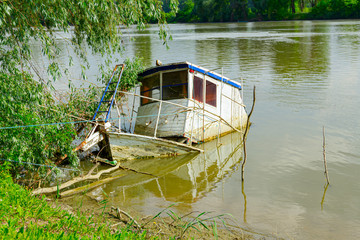 Sunken shipwreck on coast of the wide river after flood