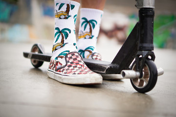 Close-up of a young boy on a scooter. He is going to jump on the ramp and do tricks. 