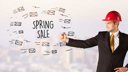 Handsome businessman with helmet drawing SPRING SALE inscription, contruction sale concept