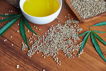 Obraz na płótnie Canvas seeds hemp on the table, oil in a glass jar, cannabis leaves isolated on white background