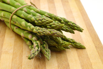 Bunches of asparagus tied with twine on a wood background. Overhead view in horizontal format.