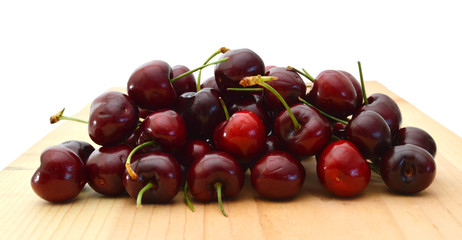 crowded group of ripe cherries, making approach on wooden board