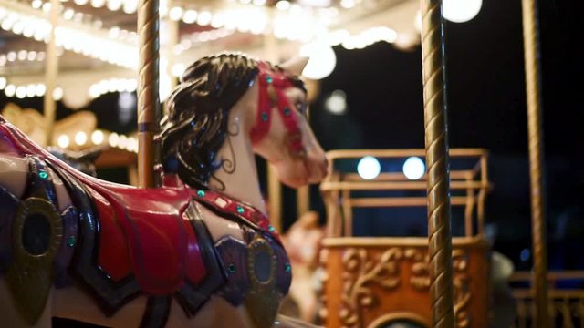 Merry go round carousel with horses spinning at funfair during night.