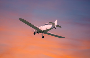 Fototapeta na wymiar Small plane in flight. Sky with beautiful colors at sunset