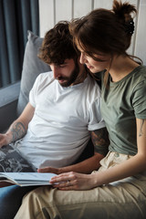 Obraz premium Lovely young couple relaxing on a couch at home, reading magazine