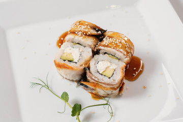 Japanese oriental cuisine. Baked sushi rolls on white plate.