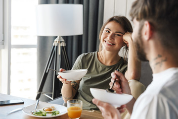 Lovely young couple having healthy breakfast in the kitchen