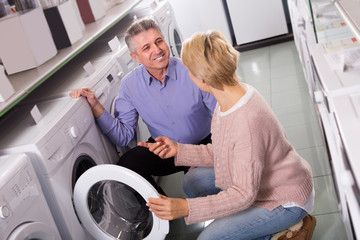 Mature married couple are choosing home modern washing machine