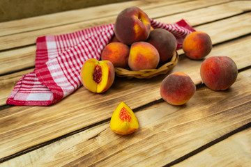 Peaches in a wicker plate and a red napkin close-up. Wooden