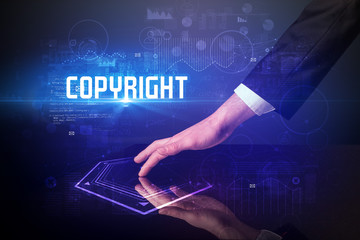 Hand touching digital table with COPYRIGHT inscription, new age security concept