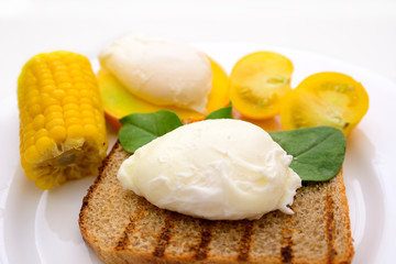 poached egg on a plate with croutons, tomato and corn	
