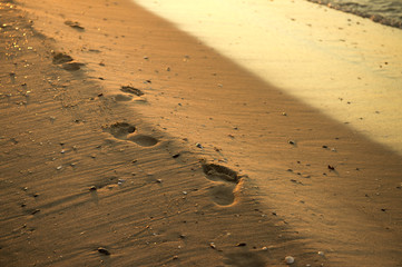 Foot prints at sand in sunrise on sea beach. Steps on sand.
