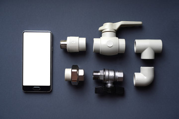 Plumbing background with fittings and empty white smartphone screen. Top view.