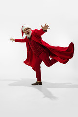 Greeting man. Modern stylish Santa Claus in red fashionable suit isolated on white background. Looks like a rockstar. New Year and Christmas eve, celebration, holidays, winter's mood, fashion.