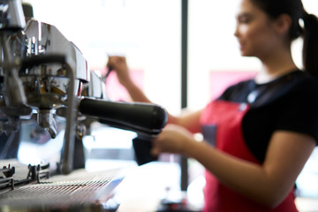Selective focus on modern automatic machine with professional metal equipment for preparation tasty coffee drinks. Blurred barista making espresso standing at contemporary appliance