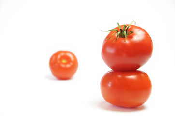 Two tomatoes standing on top of each other against a white background