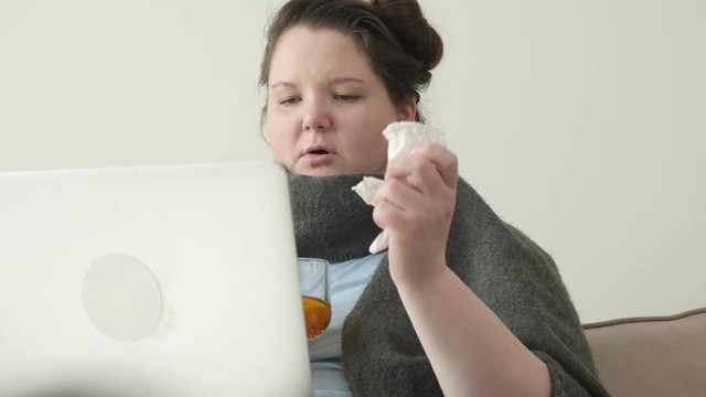 A young girl has a cold and is sitting at home on the couch. Flu, cold symptoms.