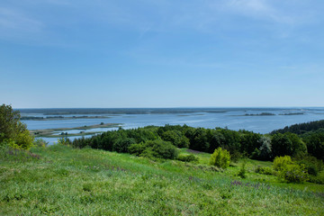 Fototapeta na wymiar View of the wide beautiful Dnieper River from the side of a large green meadow