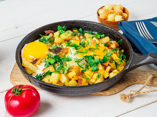 Fried eggs with potato in cast iron pan.
