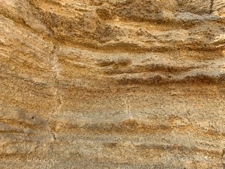 Steep cliff of the mountain by the sea. Sandy mountain by the ocean. A hill near the coast.