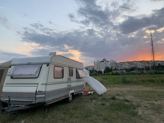 Mobile home at sunset background. Trailer for family outdoor recreation. The house is a van, opposite the residential building.