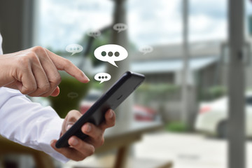 Hand using mobile phone typing, with chat icons. Social media and technology concept.