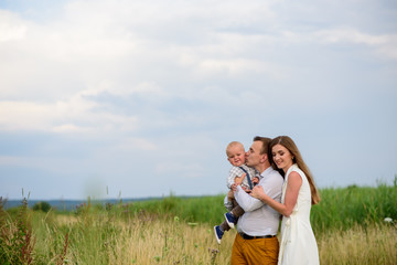 Father and mother hug their one-year-old son together.