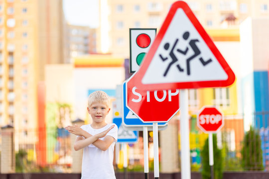 a child stands at a STOP sign and holds his hands in a cross, traffic rules for children