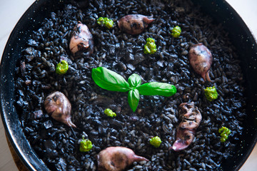 Black rice paella with chipirones and pesto made with pistachio and basilicum