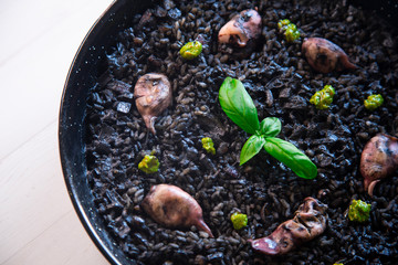 Black rice paella with chipirones and pesto made with pistachio and basilicum