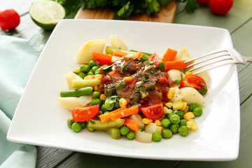 Plate with tasty conchiglie pasta and vegetables on table