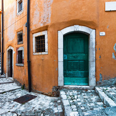 Italian old building, vibrant color alleyway in Italy. Yellow wall and a green wood door. - 372700090