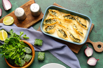 Baking dish with tasty conchiglioni pasta on color background