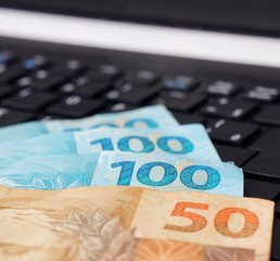 Brazilian money on computer keyboard. Online shopping concept.
