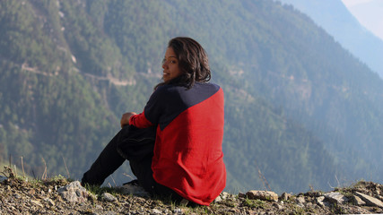 Naklejka premium Young Indian Female Sitting on the edge of the mountain