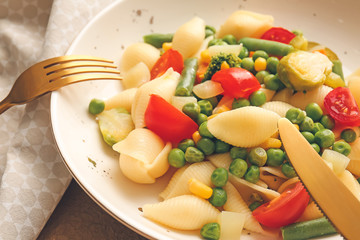 Plate with tasty conchiglie pasta and vegetables, closeup