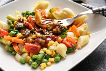 Plate with tasty conchiglie pasta and vegetables, closeup