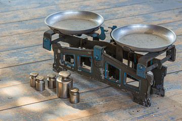 old balance scales with weights on a shabby wooden floor