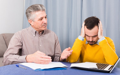 Mature father and young son are discussing an important contract at table